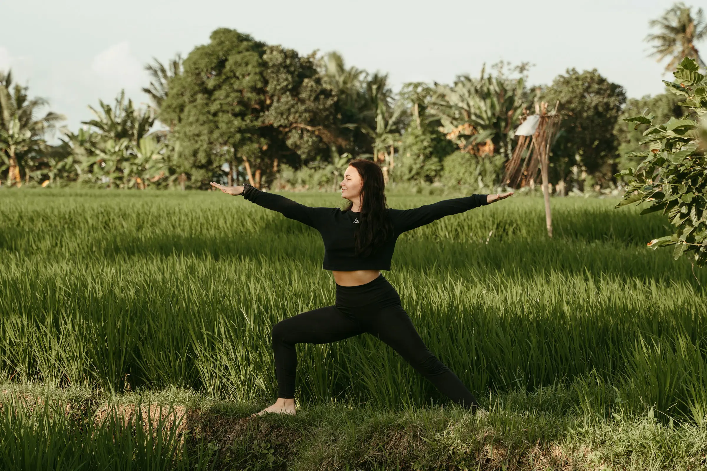 Woman dressed in black practicing yoga in nature in Bali