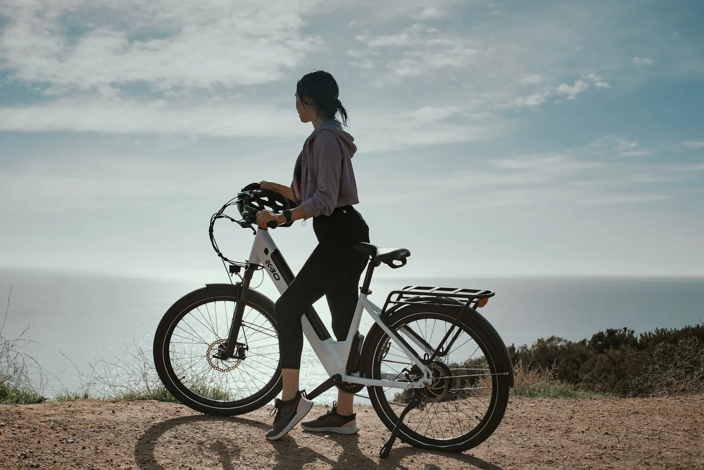 Woman on bike looking out over the coast and sea in Mallorca