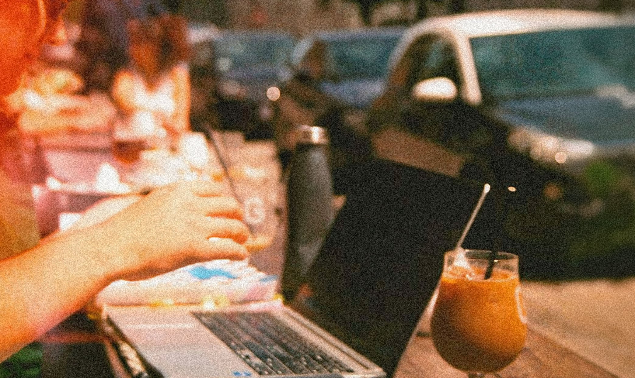 Person arbetar på en laptop från ett café under en bleisure-resa. Bild som illustrerar hur affärsresor kan kombineras med semester, distansarbete och flexibilitet.