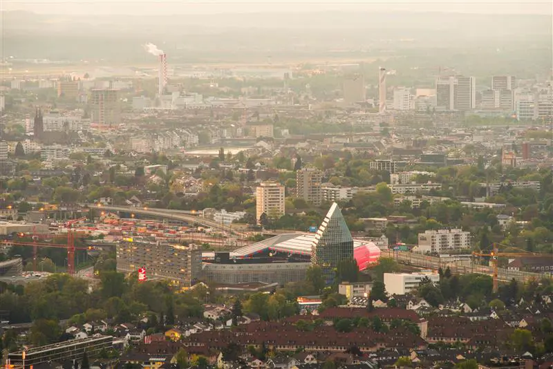 Flygbild över en stad med moderna byggnader och infrastruktur, dimmigt ljus över skyline.