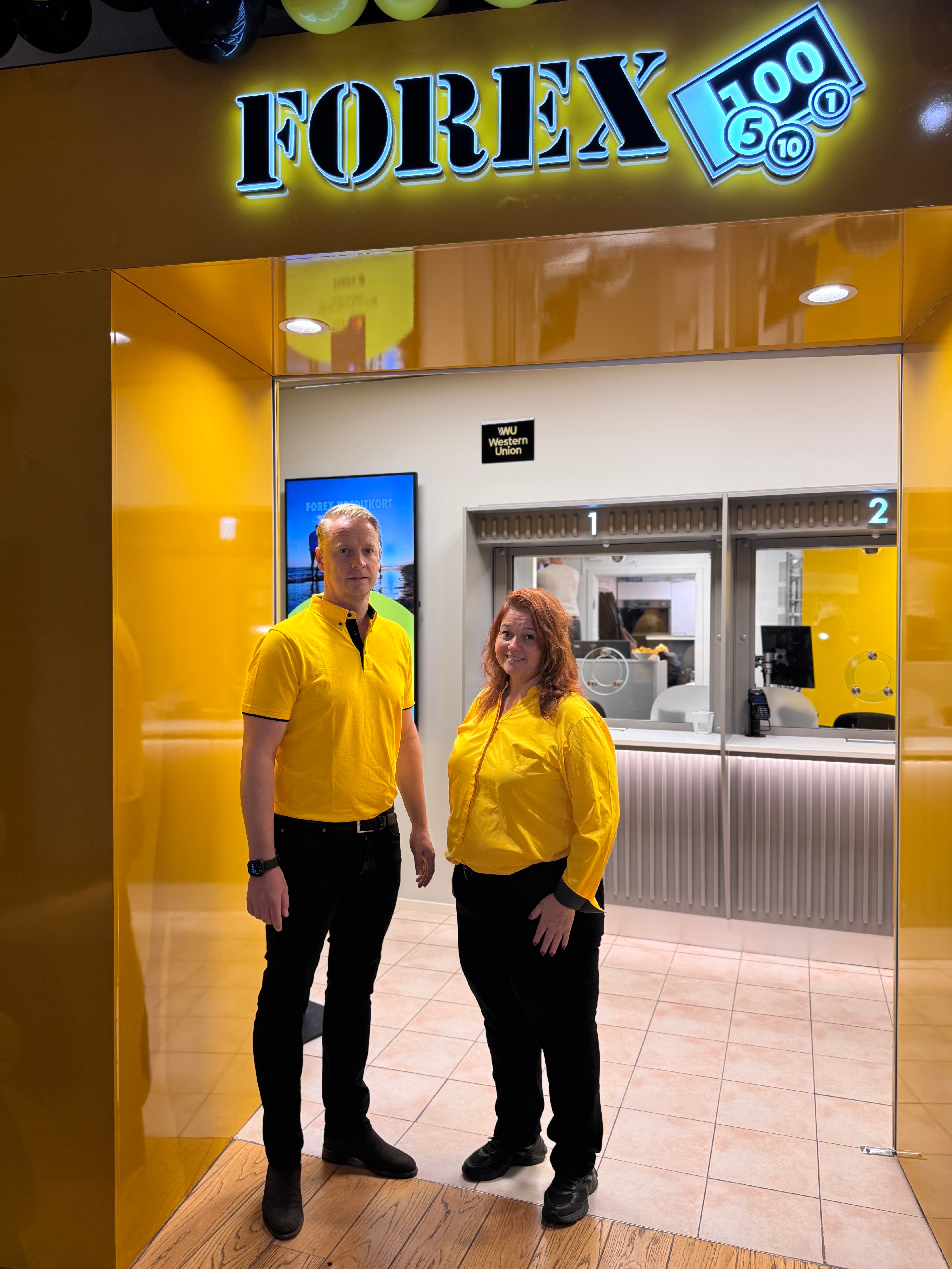 Två personer i gula skjortor står framför en nyöppnad FOREX-butik i Triangeln, Malmö.