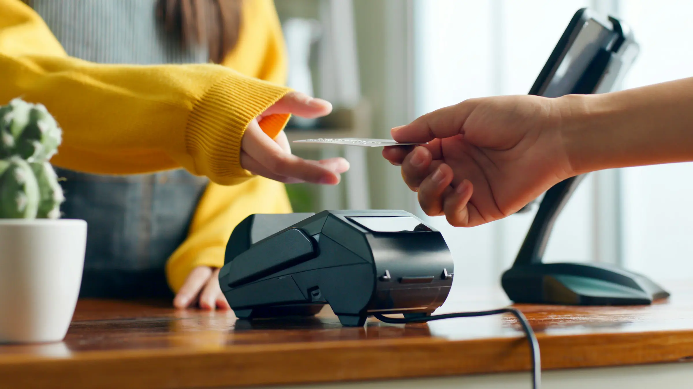 Customer making a contactless payment with a credit card at a point-of-sale terminal in a retail setting.