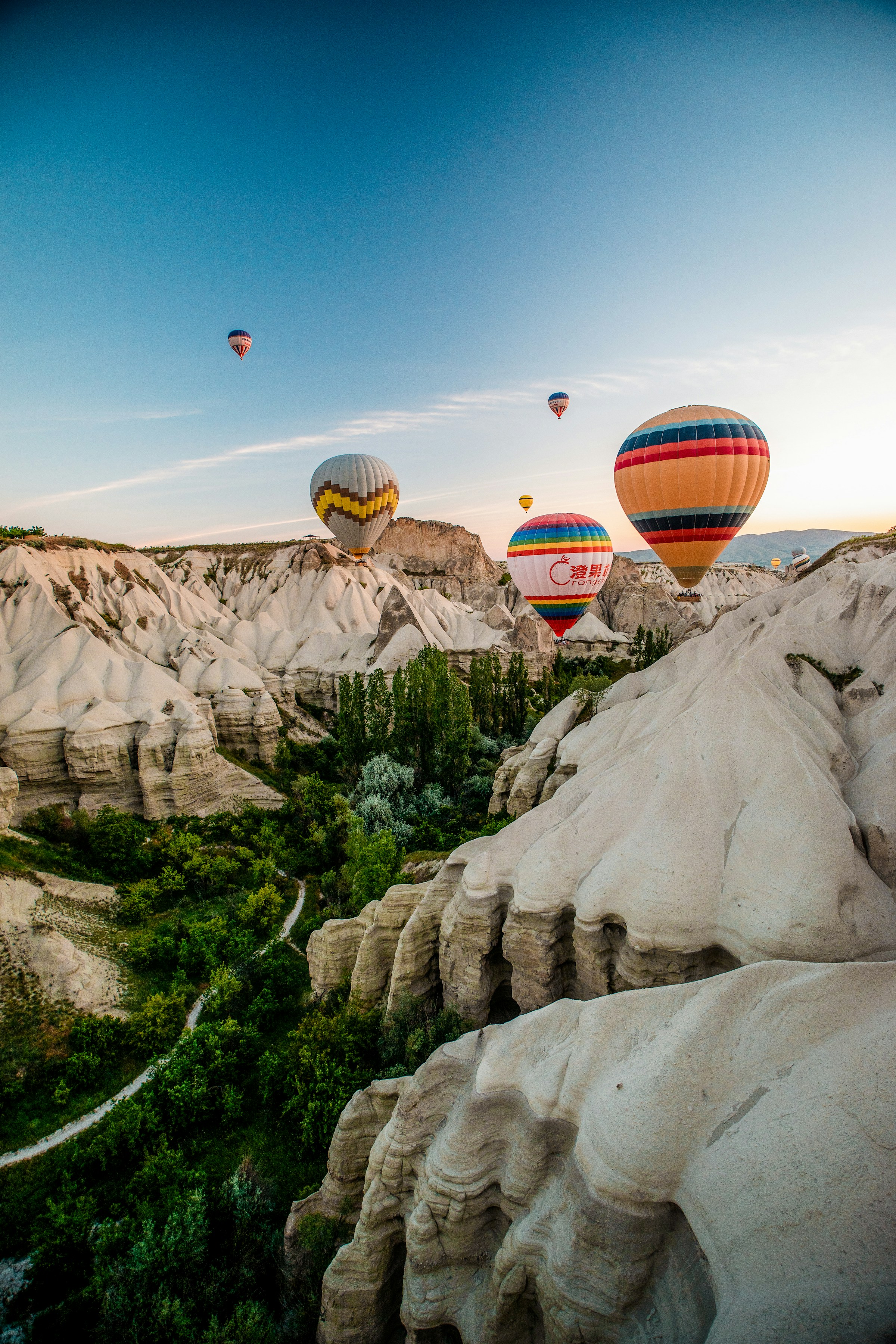 Luftballonger svävar över Cappadociens karakteristiska bergformationer vid solnedgången, Turkiet.