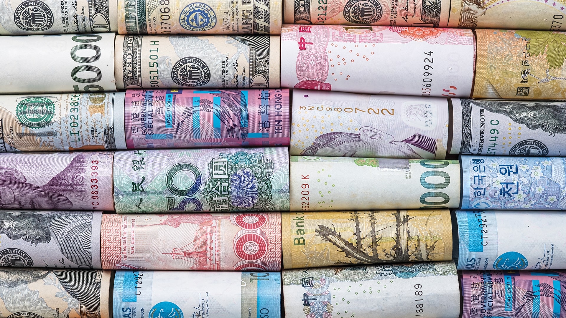 Växla pengar och valuta - Olika internationella valutor i färgglada sedelrullar placerade sida vid sida.