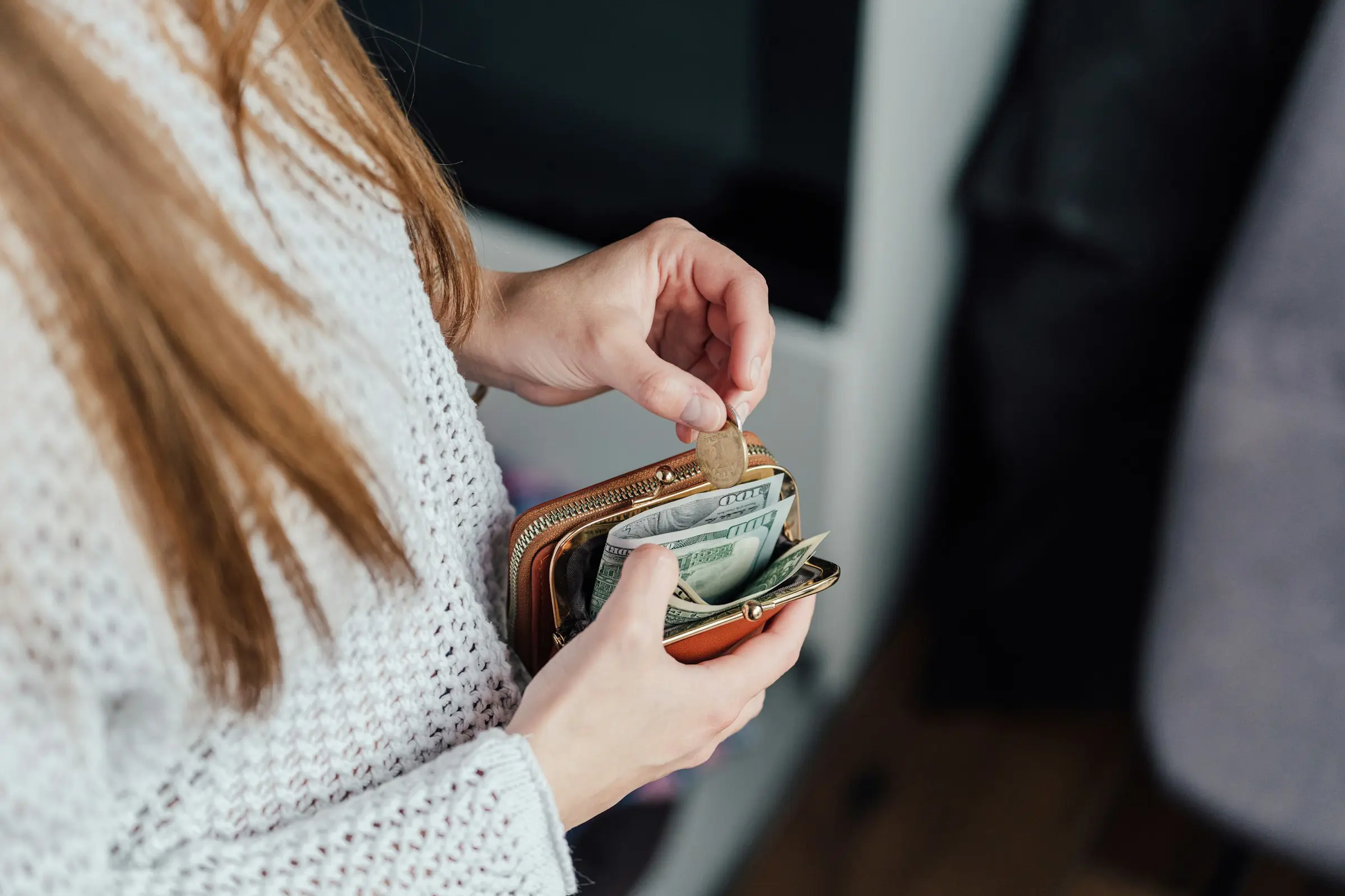 Person som håller i en plånbok med kontanter och mynt, hanterar sin privatekonomi hemma