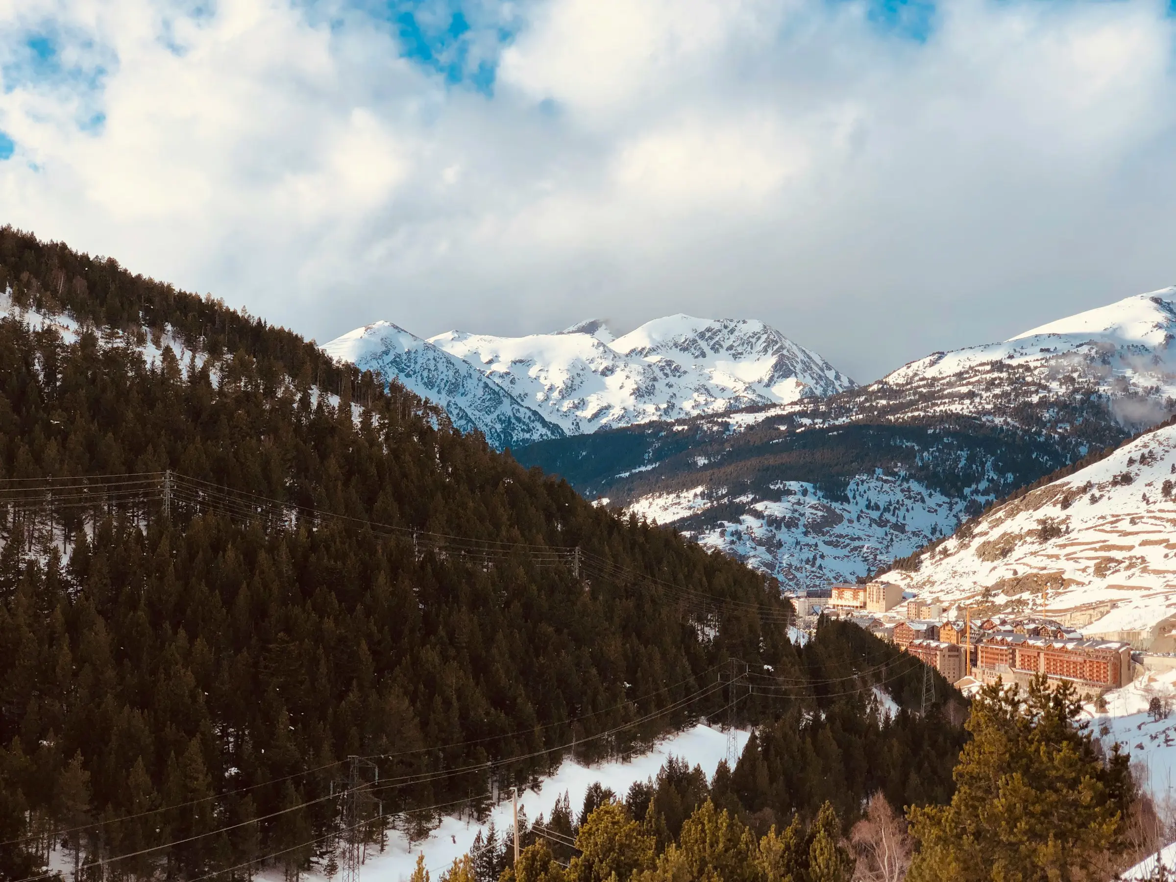 Vy över snötäckta bergskedjor i Grandvalira, Andorra men ett skidresort nedanför