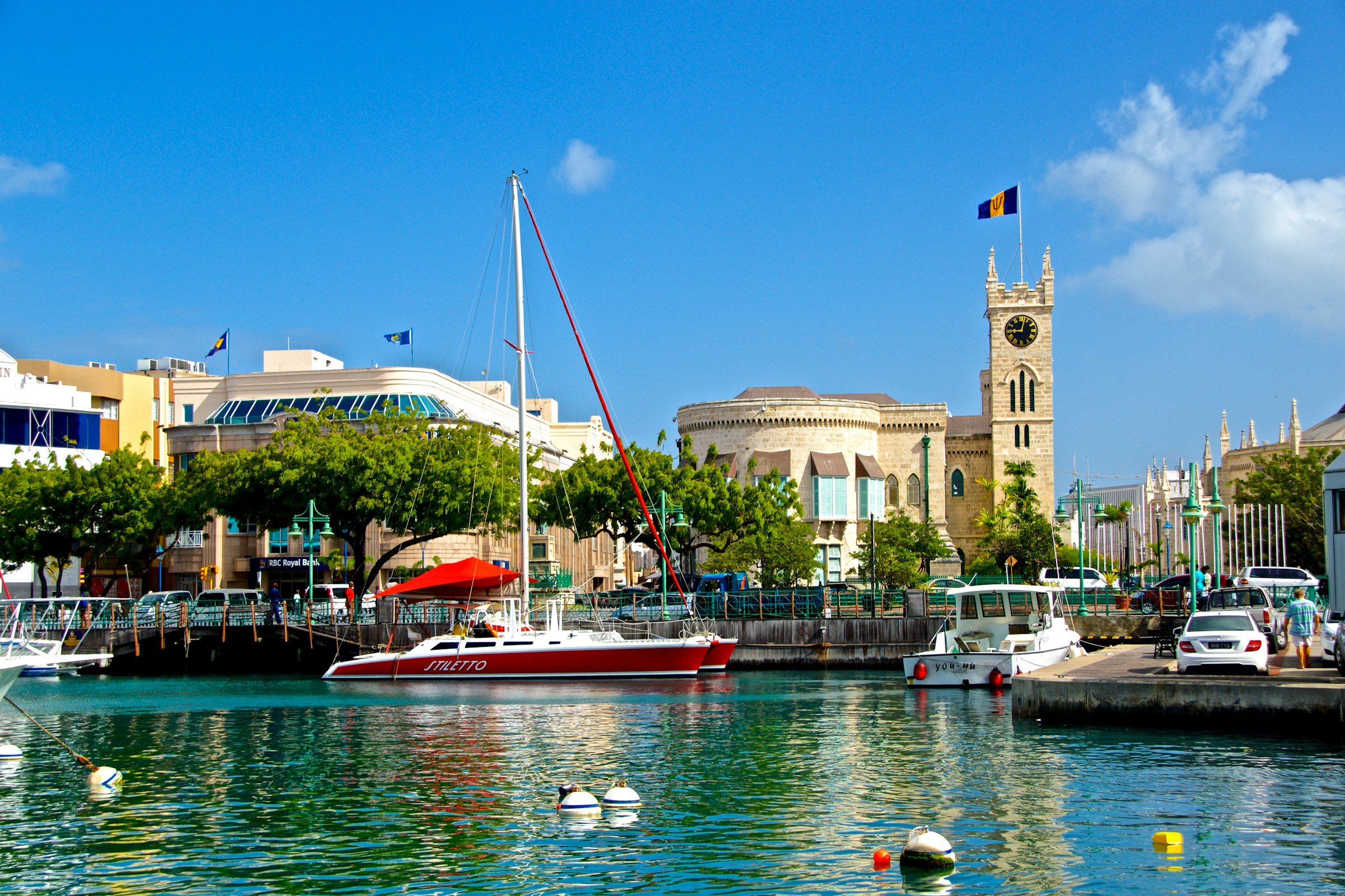 View of Bridgetown, Barbados, featuring boats docked along the harbor and the iconic clock tower of St. Michael's Cathedral.