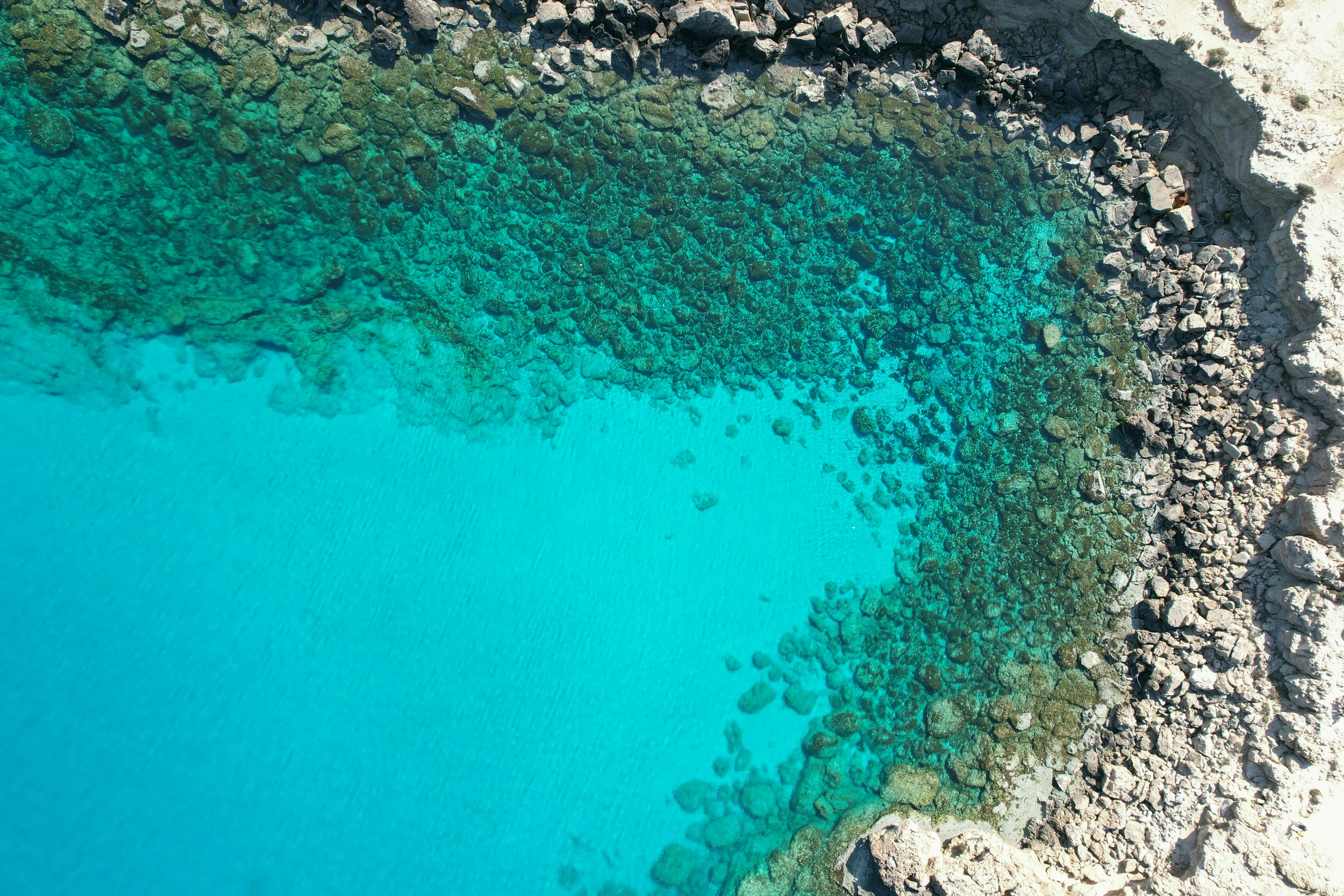 Aerial view of crystal-clear turquoise water surrounded by rocky coastline.