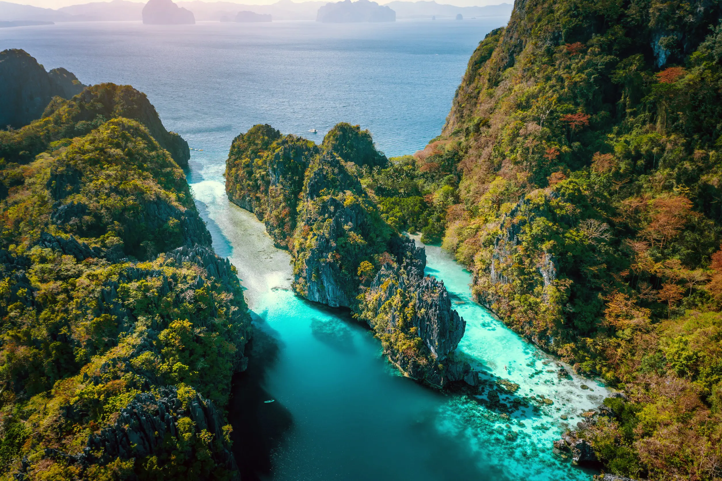 Travel to Philippines - View of tropical lagoon surrounded by lush green cliffs in El Nido, Palawan with clear turquoise water leading to the ocean.