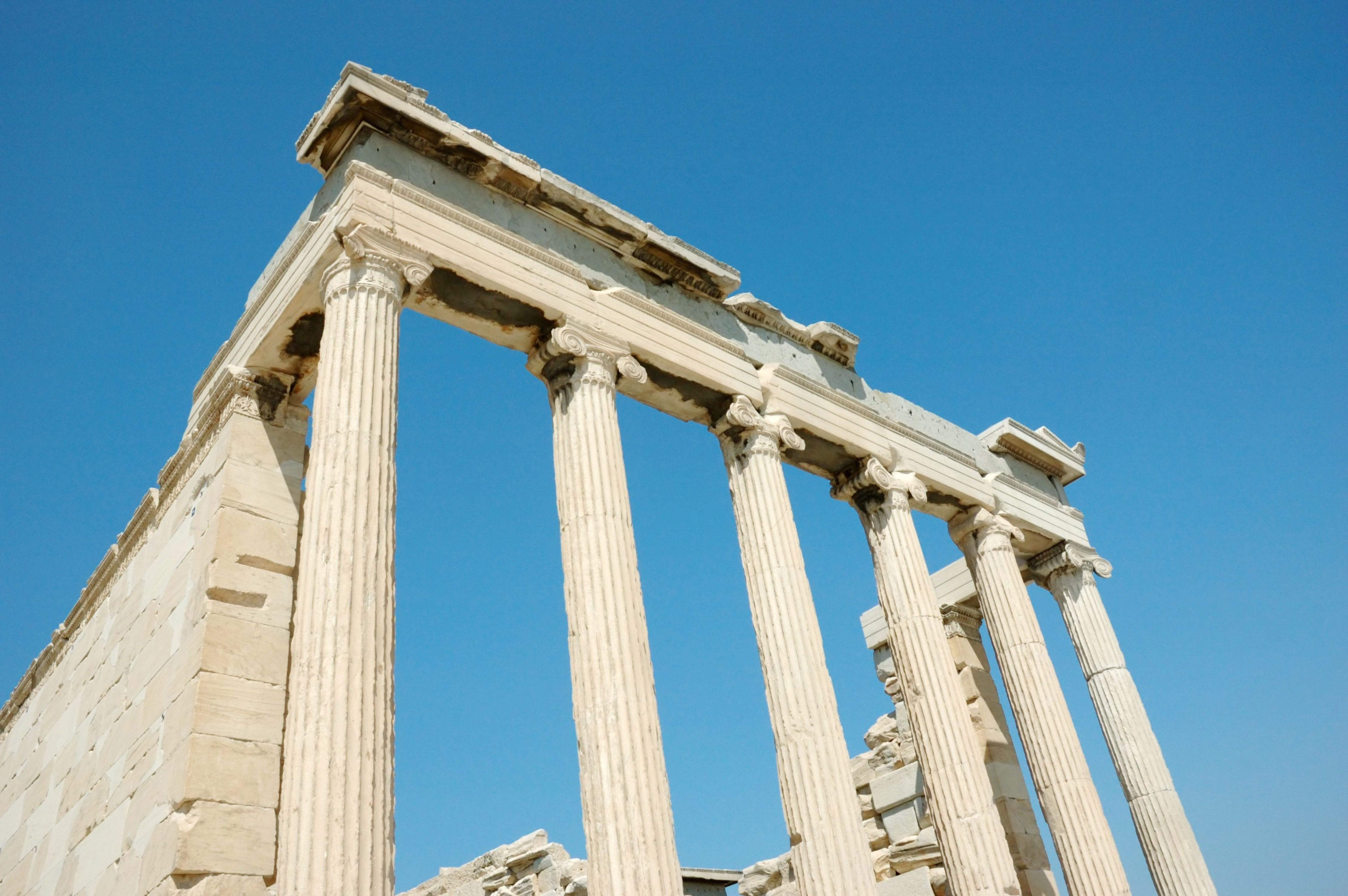 Travel to Athens - Ancient Greek ruins with Doric columns against a clear blue sky.