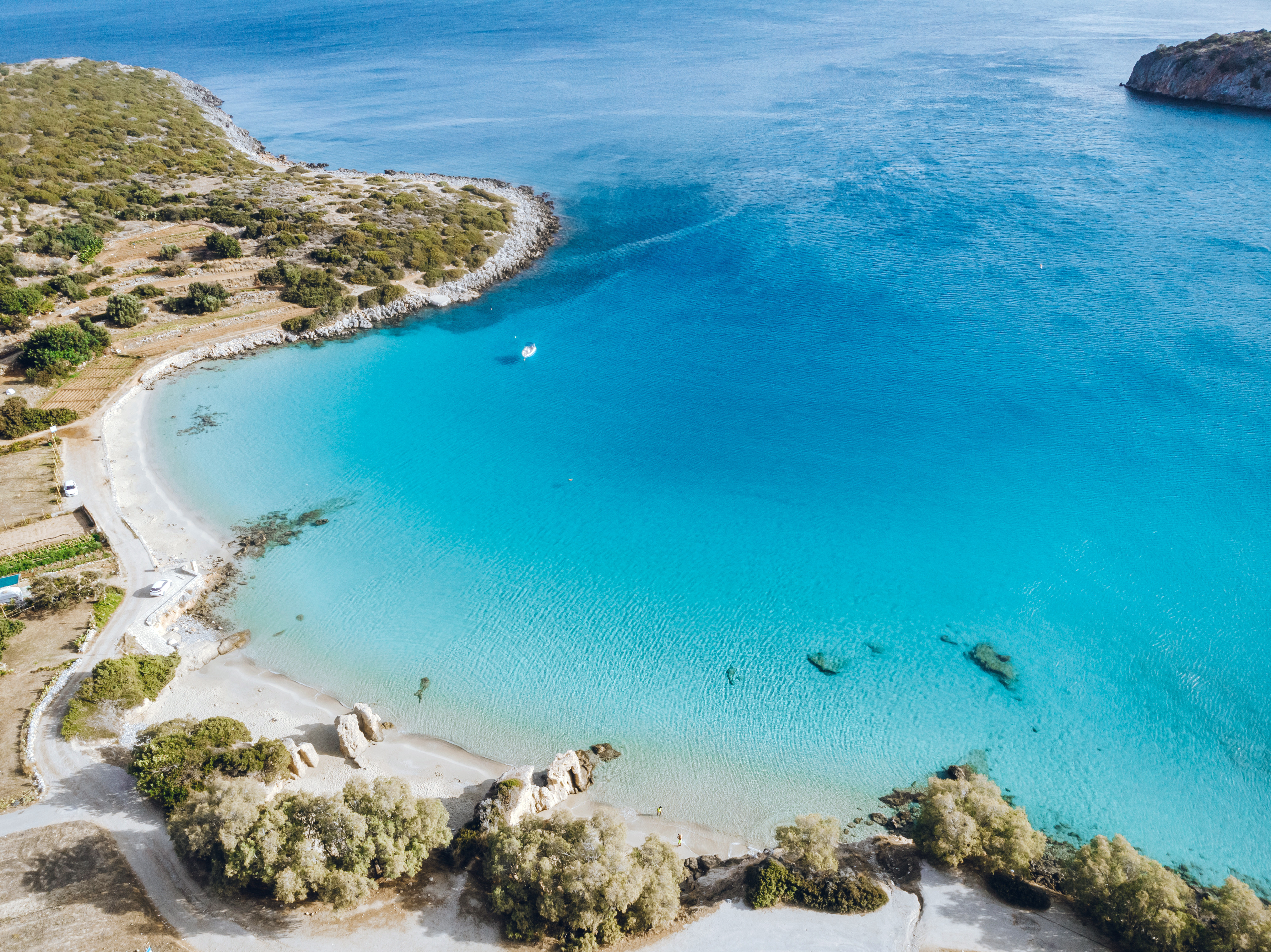 Resa till Kreta - Flygbild över idyllisk kustlinje med kristallklart turkos vatten och grön vegetation.