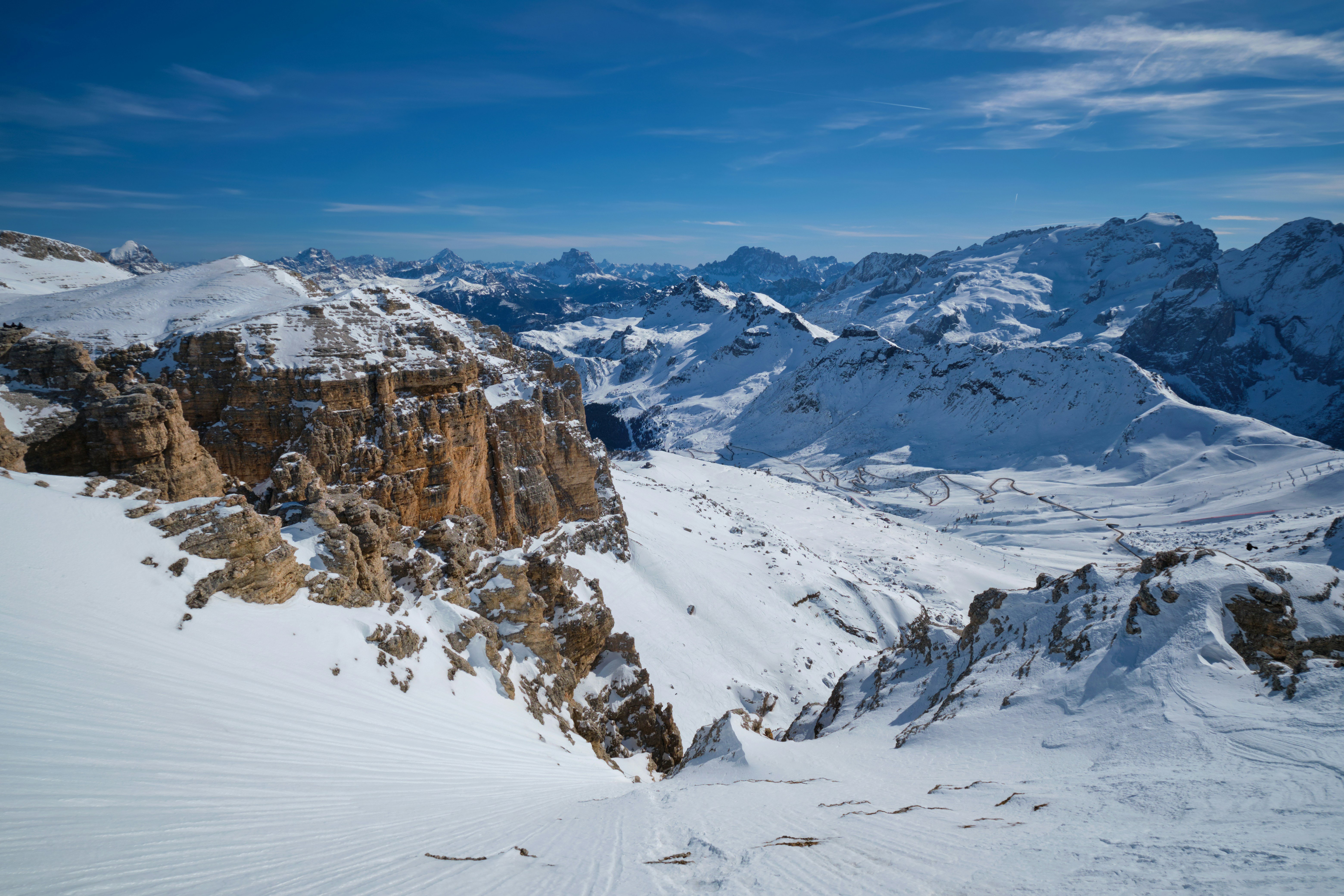 Resa till Canazei - Vy och utsikt över snötäckta Dolomiterna i Canazei med blå himmel och bergskedja i bakgrunden