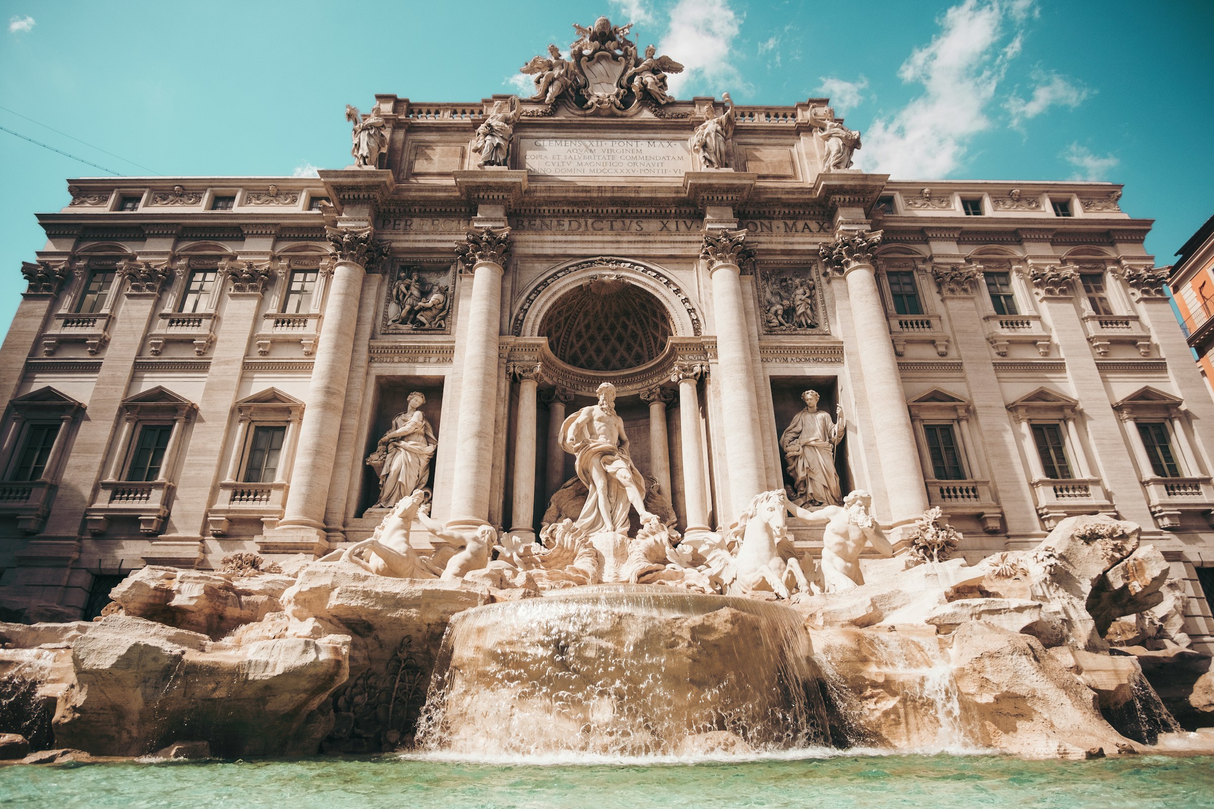 Trevi Fountain in Rome, Italy under a clear blue sky, showcasing Baroque sculptures and flowing water.