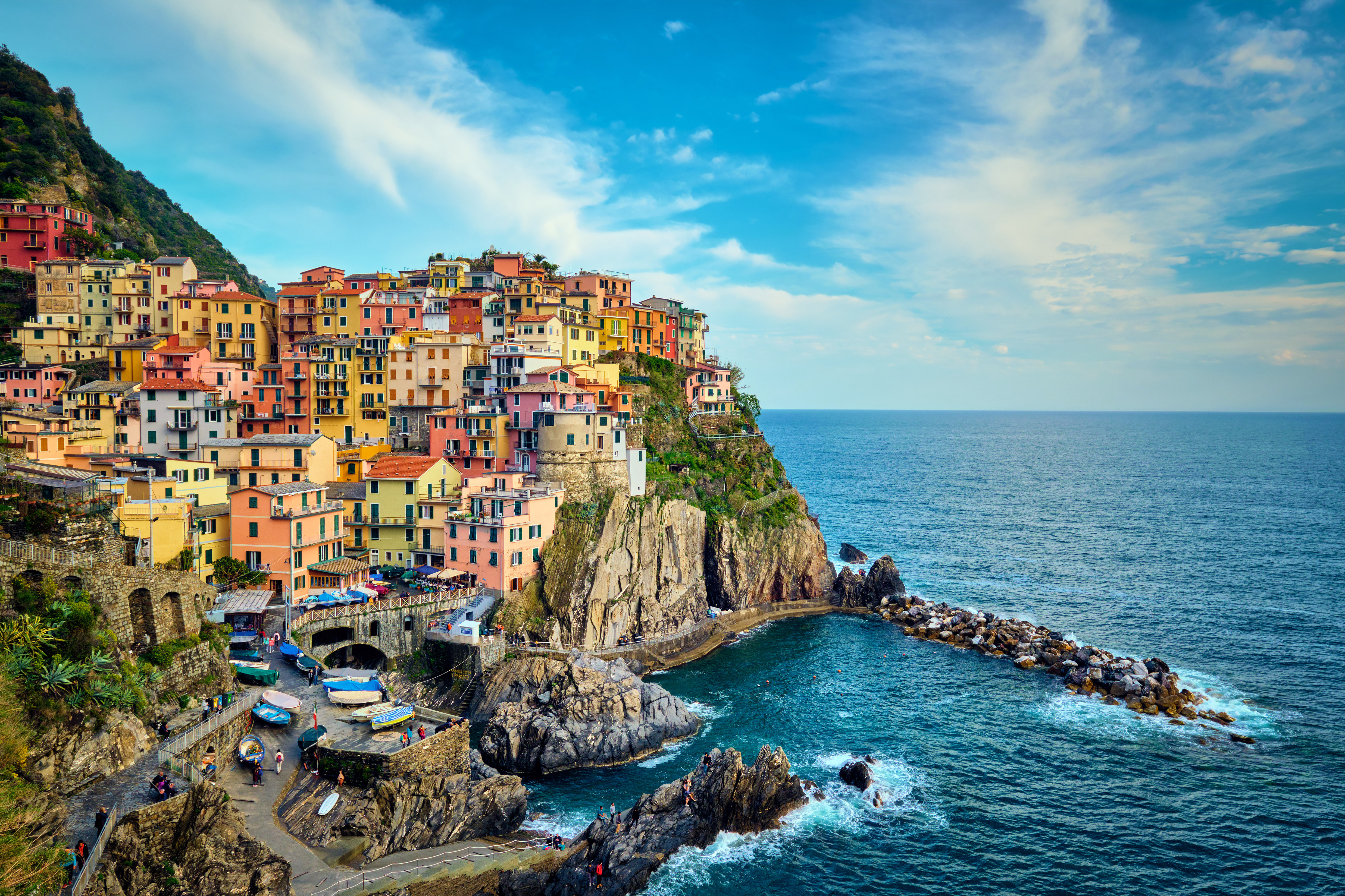 Travel to Italy - Colorful cliffside houses overlooking the sea in Manarola, Cinque Terre, Italy, with a bright blue sky.