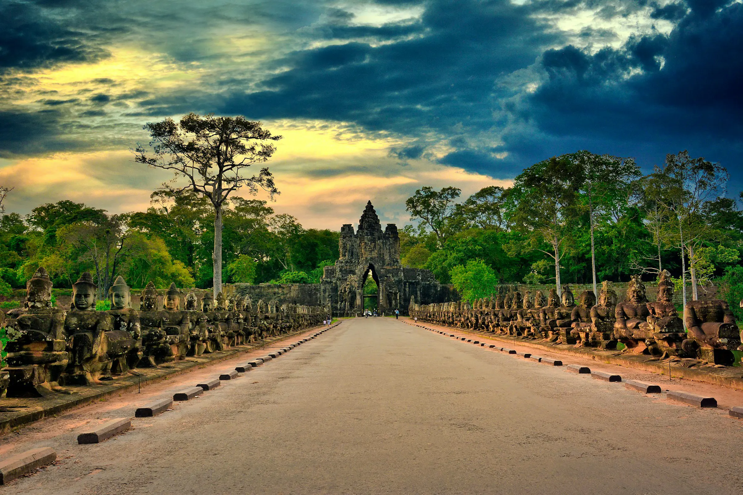 Angkor Wats södra port med skulpturer på båda sidor under en dramatisk himmel i solnedgången, Siem Reap, Kambodja.