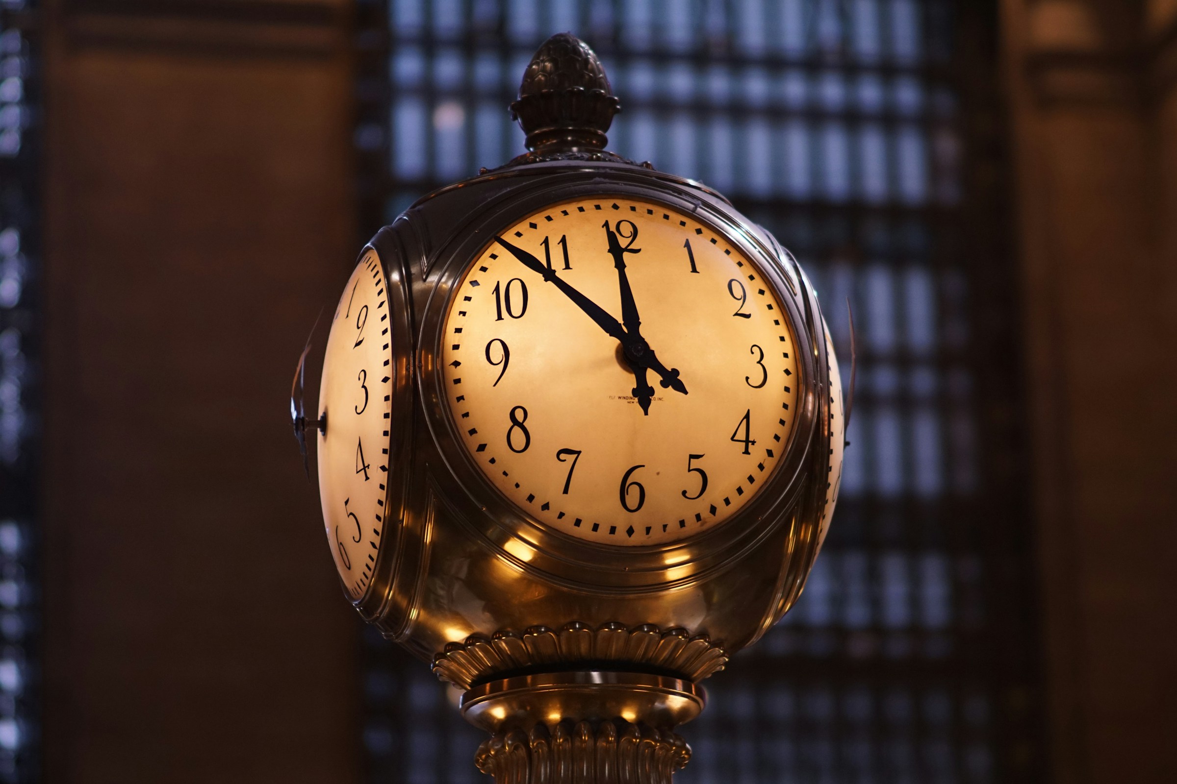 An ornate clock inside Grand Central Terminal shows the time as 10:10, set against a dimly lit, architectural background