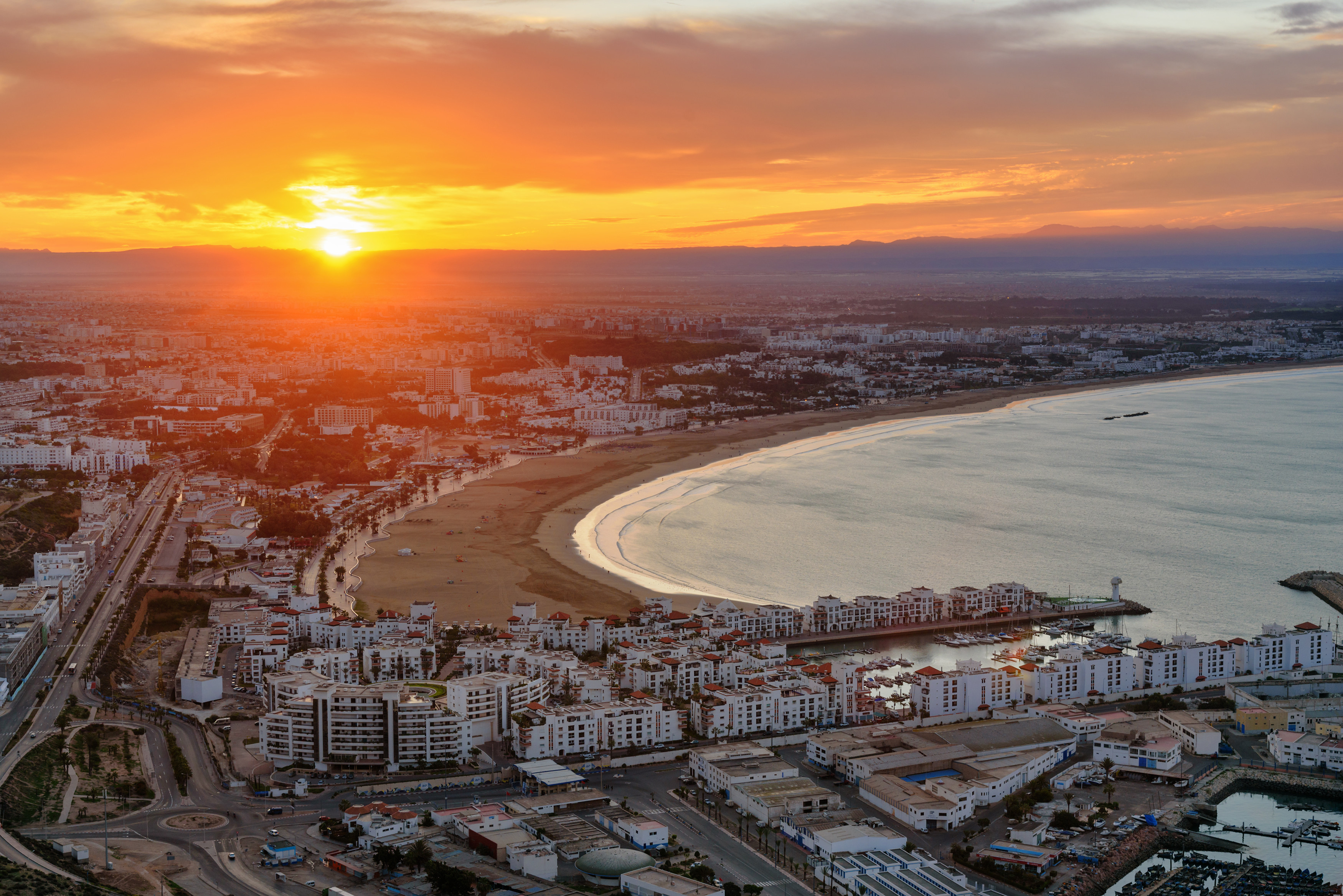 Sunset over Agadir beach and cityscape, featuring golden skies and an expansive coastline in Morocco
