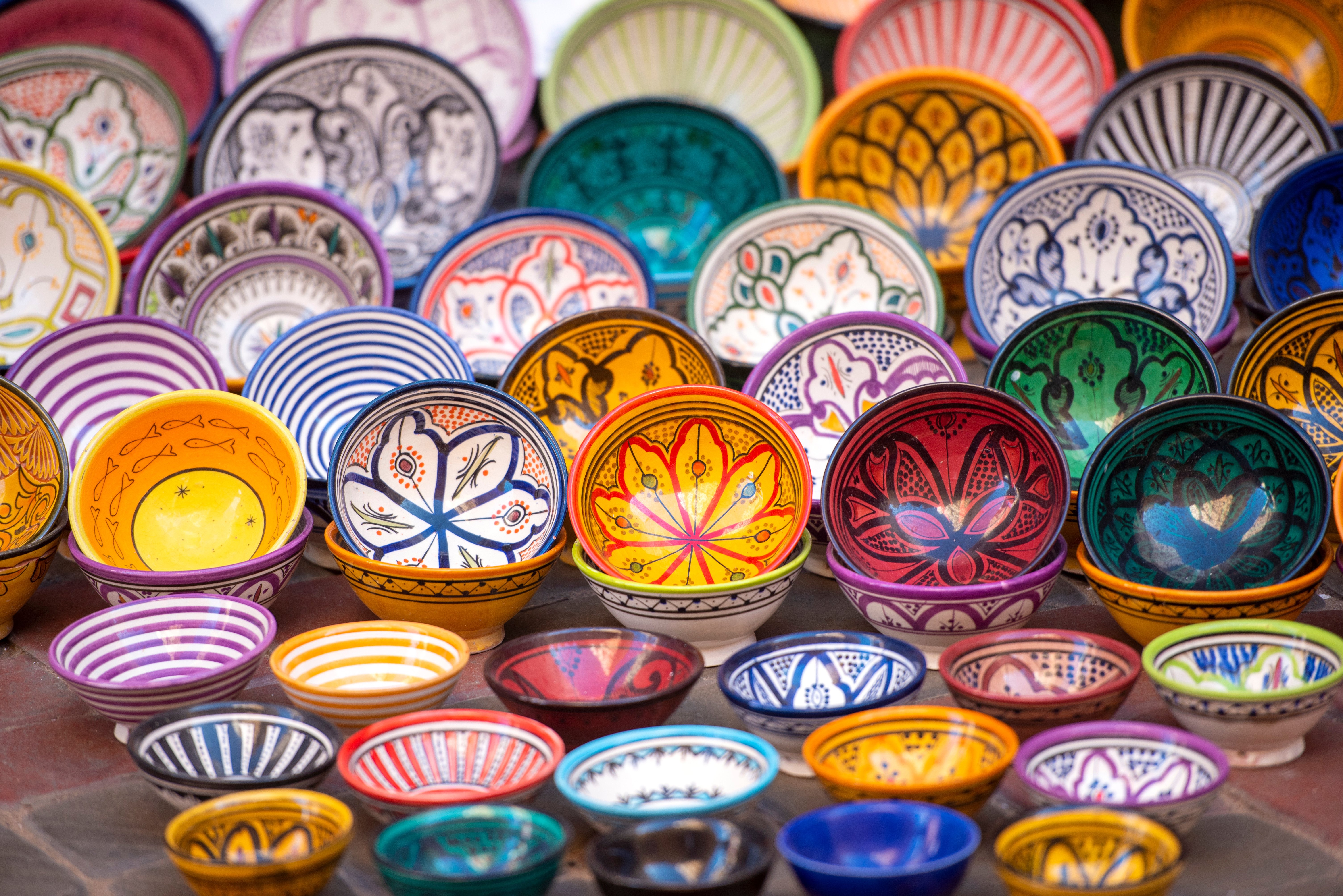 Colorful handcrafted ceramic bowls with intricate patterns displayed in a vibrant market setting
