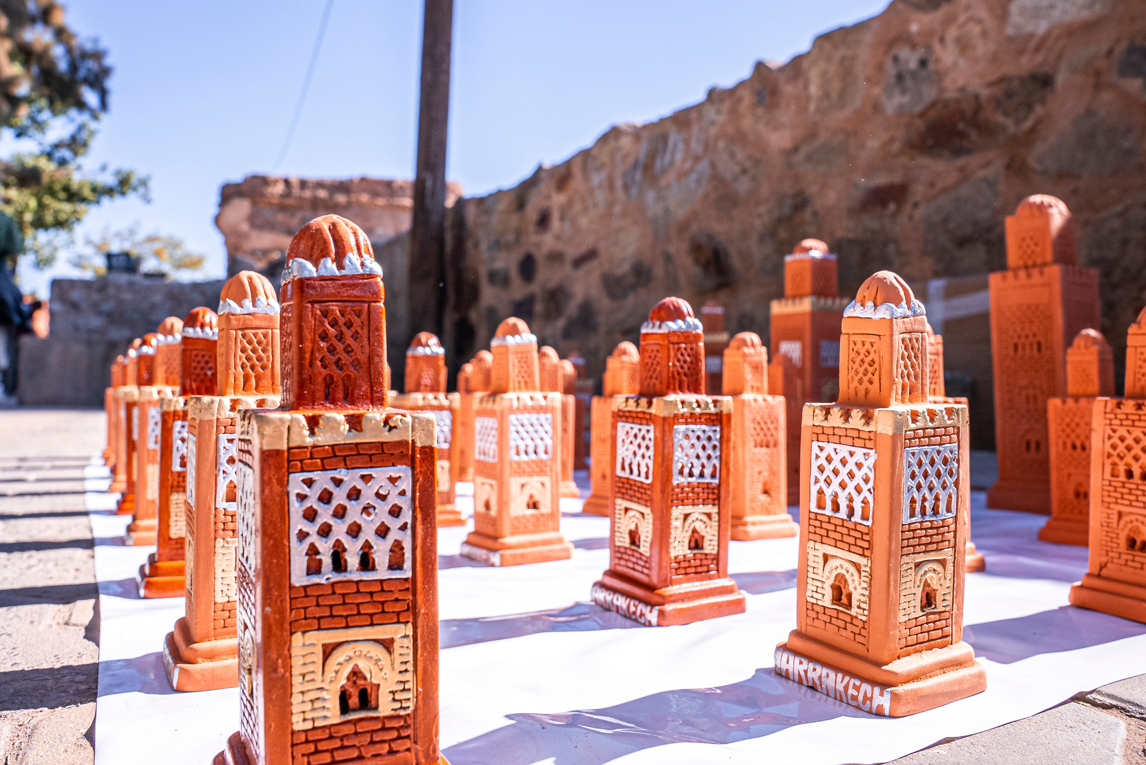 Terracotta models of Koutoubia Mosque in Marrakech, displayed on a sunny street