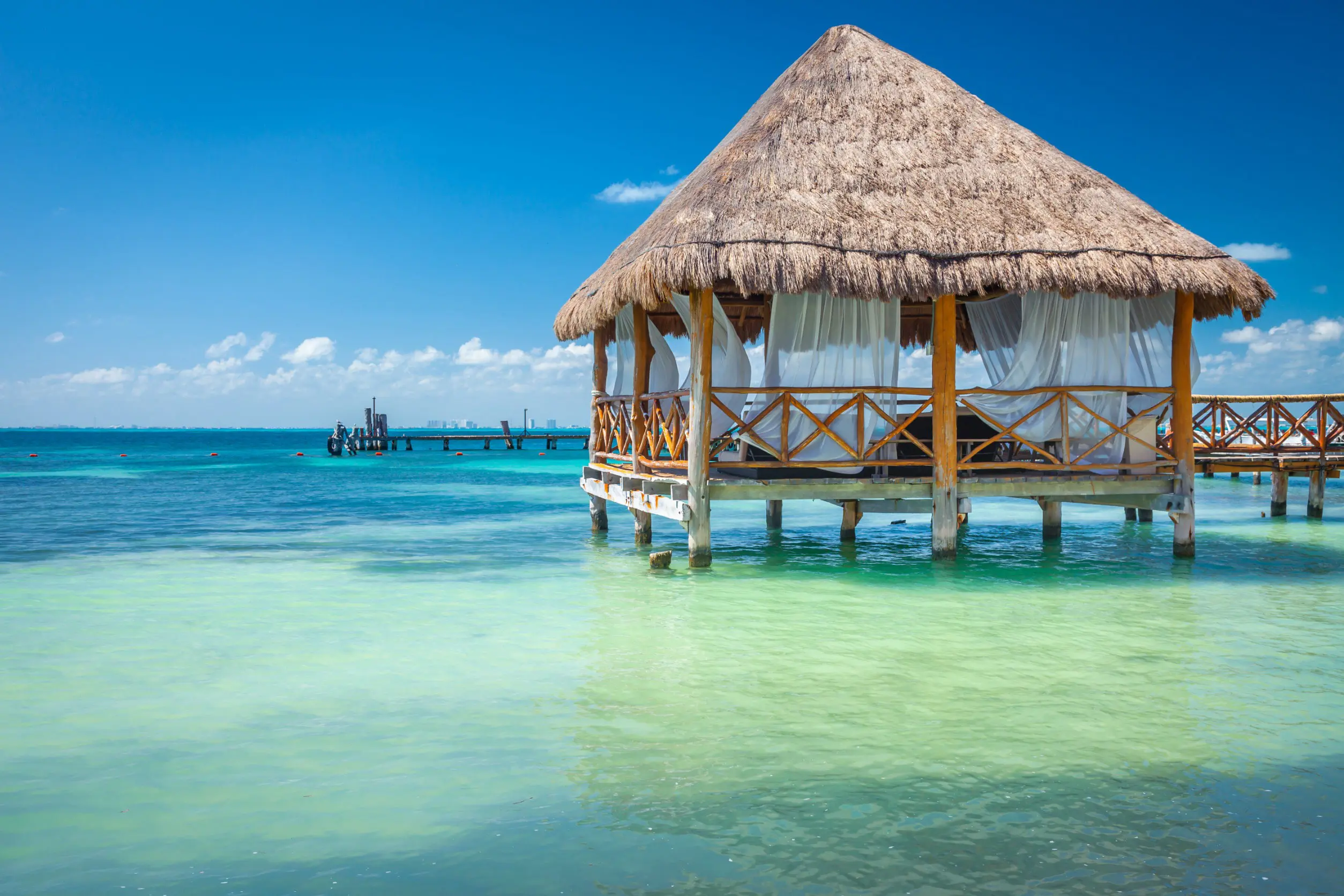 En bungalow står i vackert turkosblått vatten med blå himmel i Cancun, Mexiko
