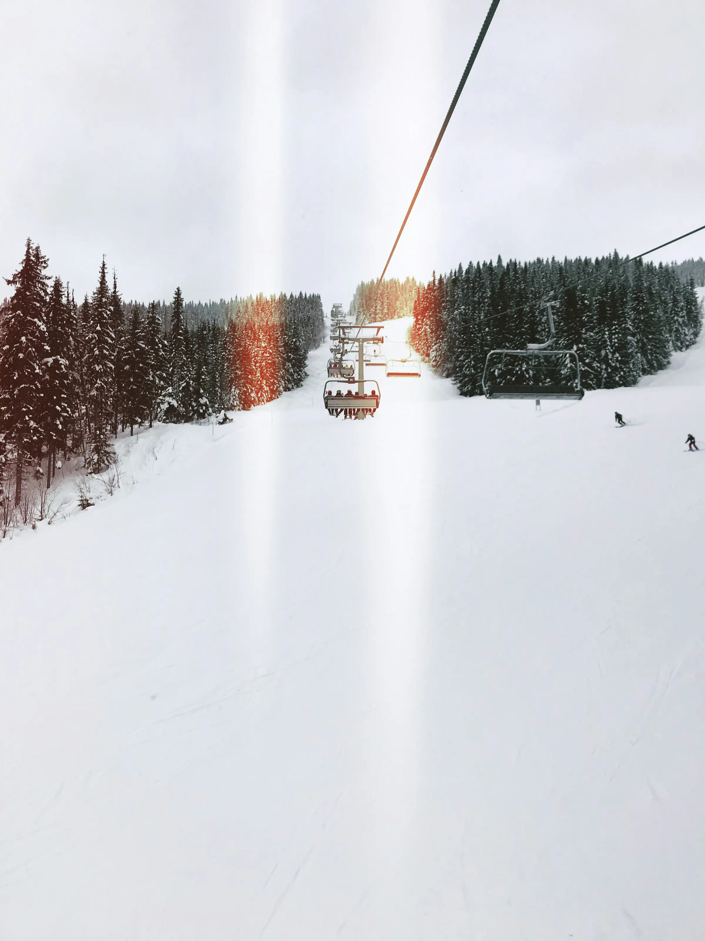 Två personer åker i en skidlift över en snötäckt skidbana i Trysil, Norge