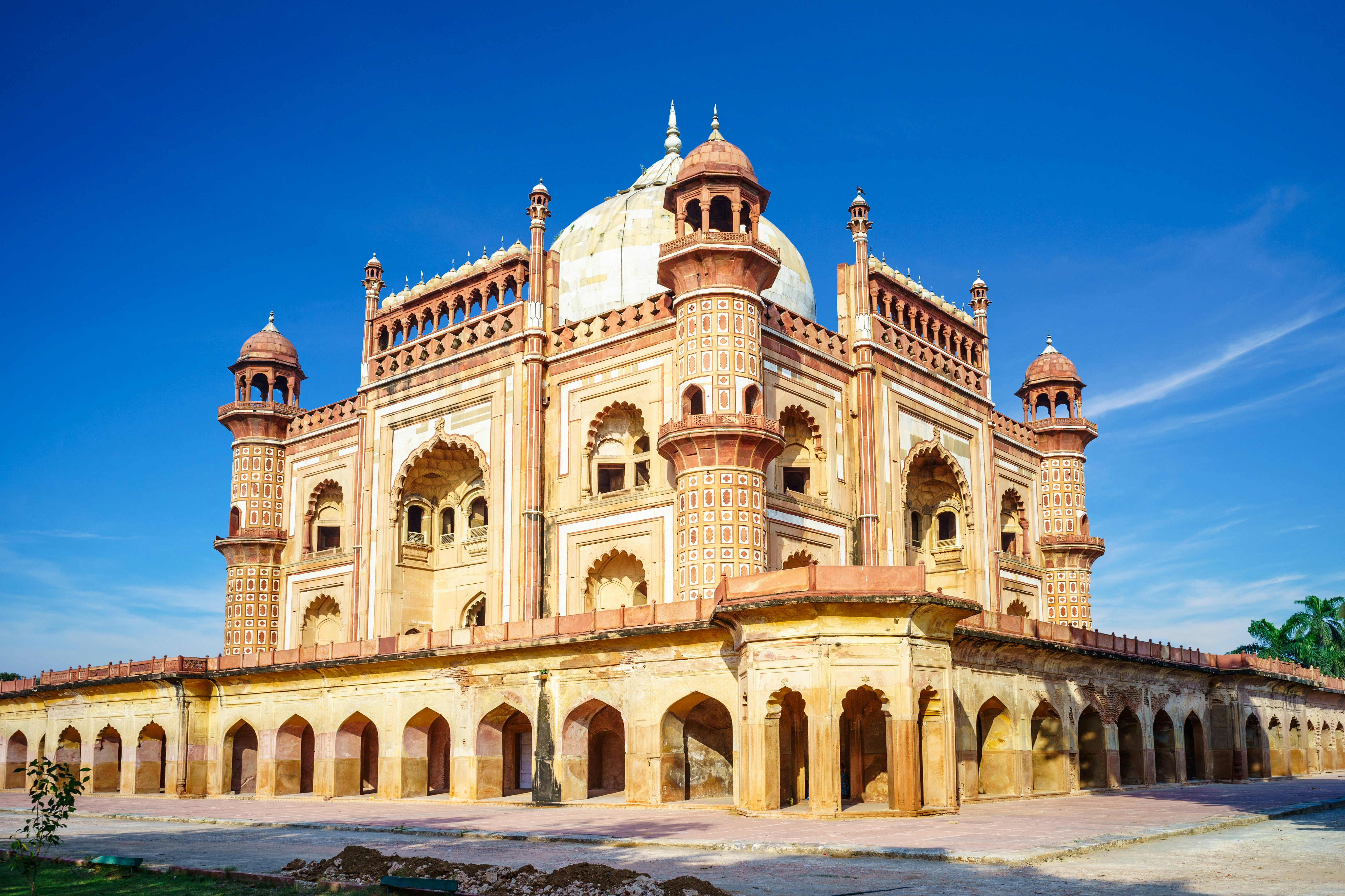 Historic Mughal architecture of Safdarjung Tomb in New Delhi, India, featuring intricate sandstone carvings and domed roofing under a clear blue sky
