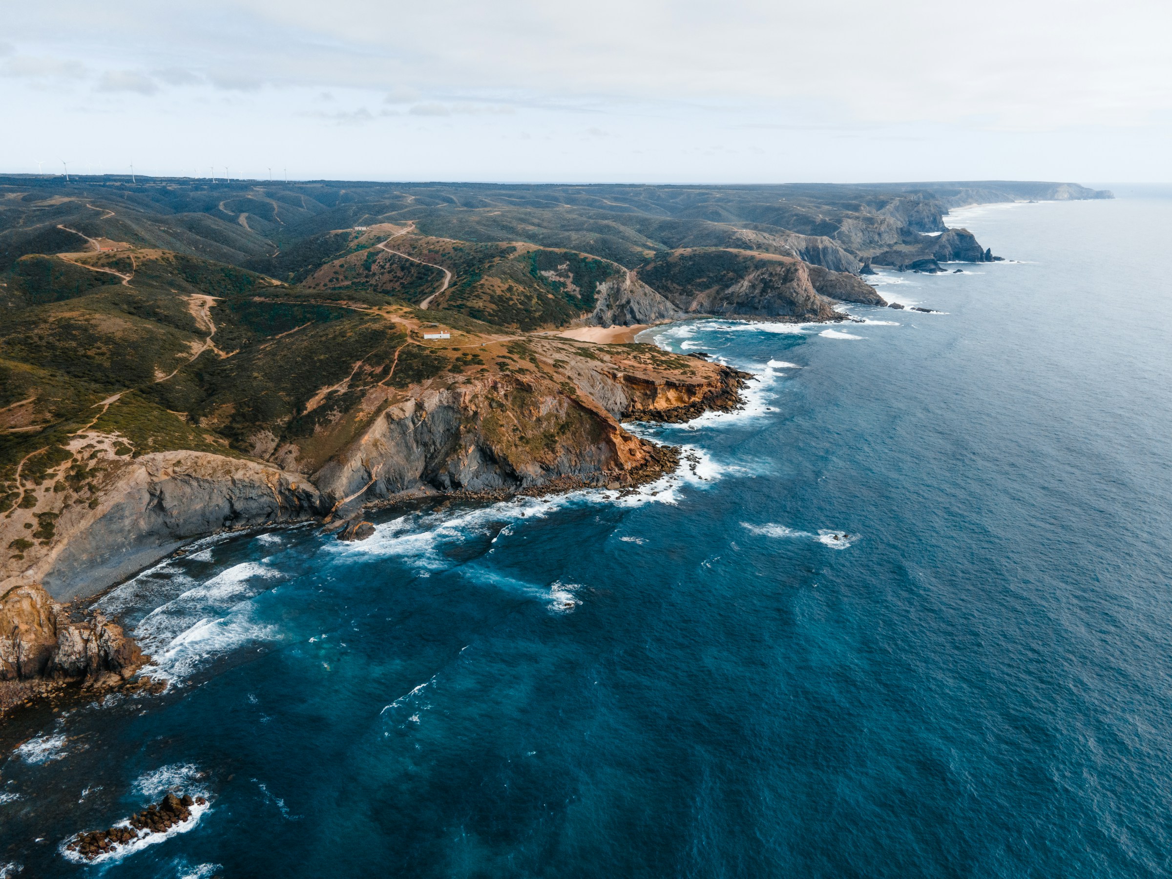 Fågelvy över kusten i Portugal där havet möter stora klippor med skog omkring sig