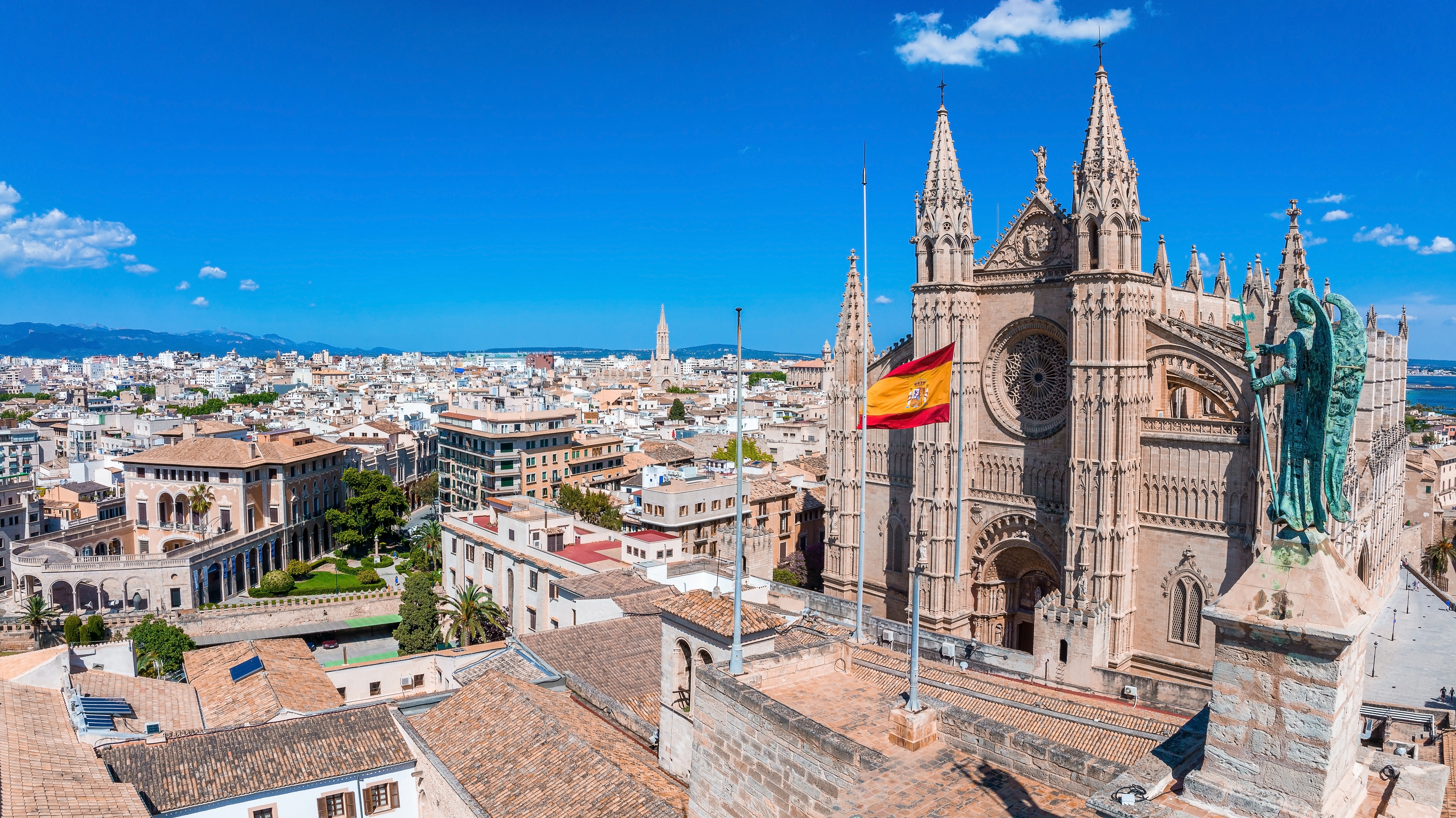 Gothic cathedral with Spanish flag in Palma de Mallorca, overlooking the cityscape on a sunny day