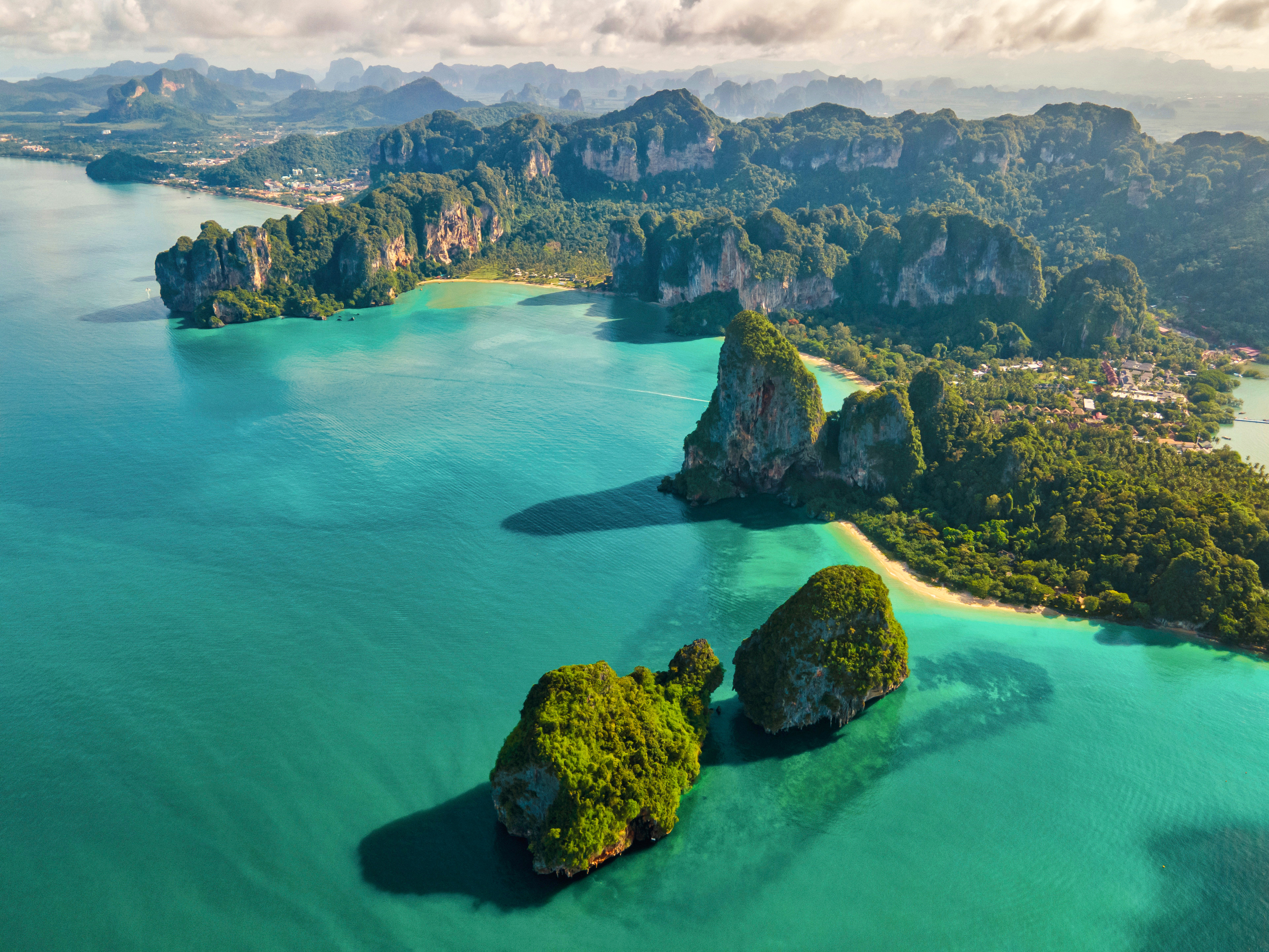 Resa till Krabi - Flygfoto över en tropisk skärgård med klart turkos vatten och kalkstensklippor i Krabi.