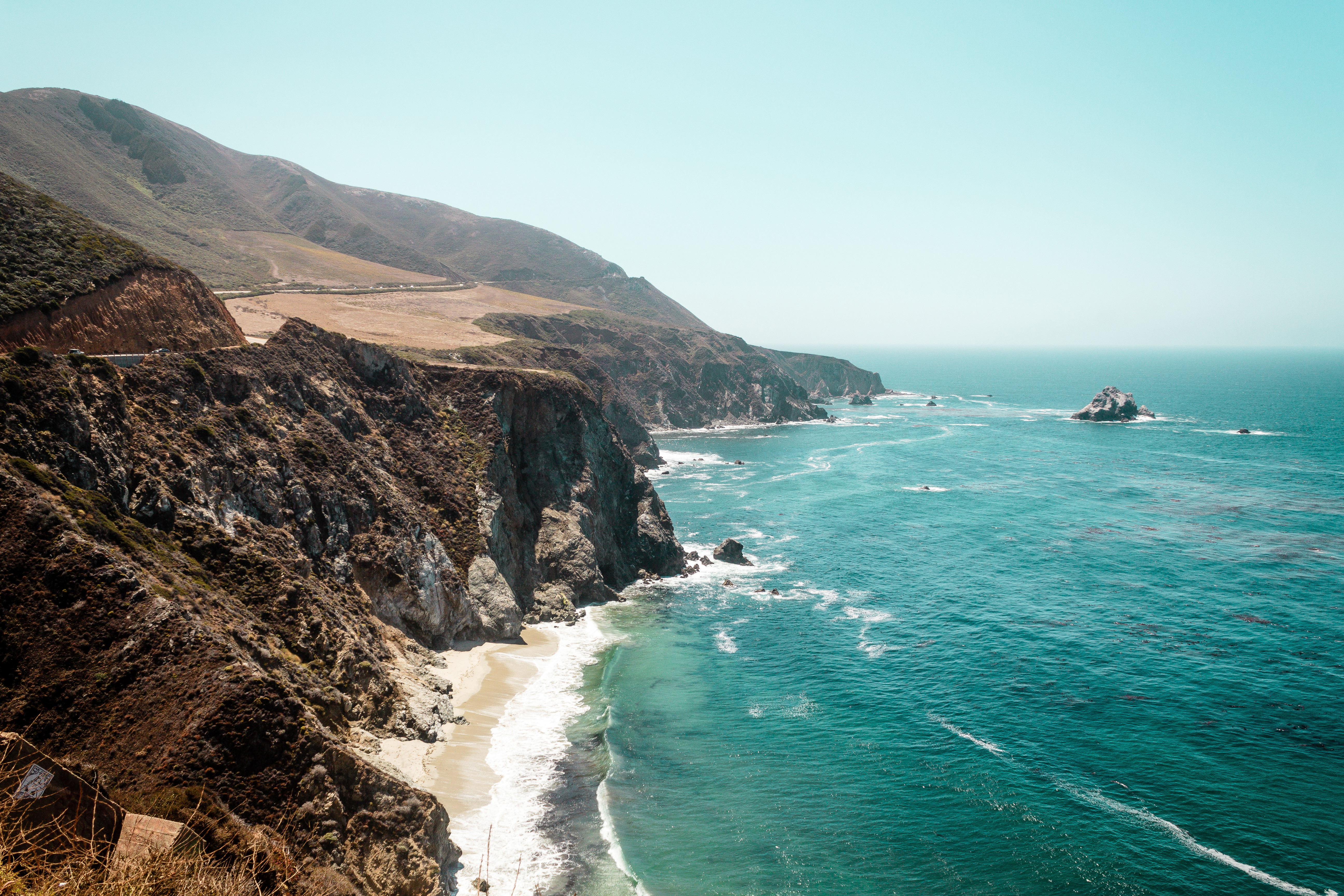 Travel to California - view of rugged cliffs along the California coastline with turquoise ocean waves.