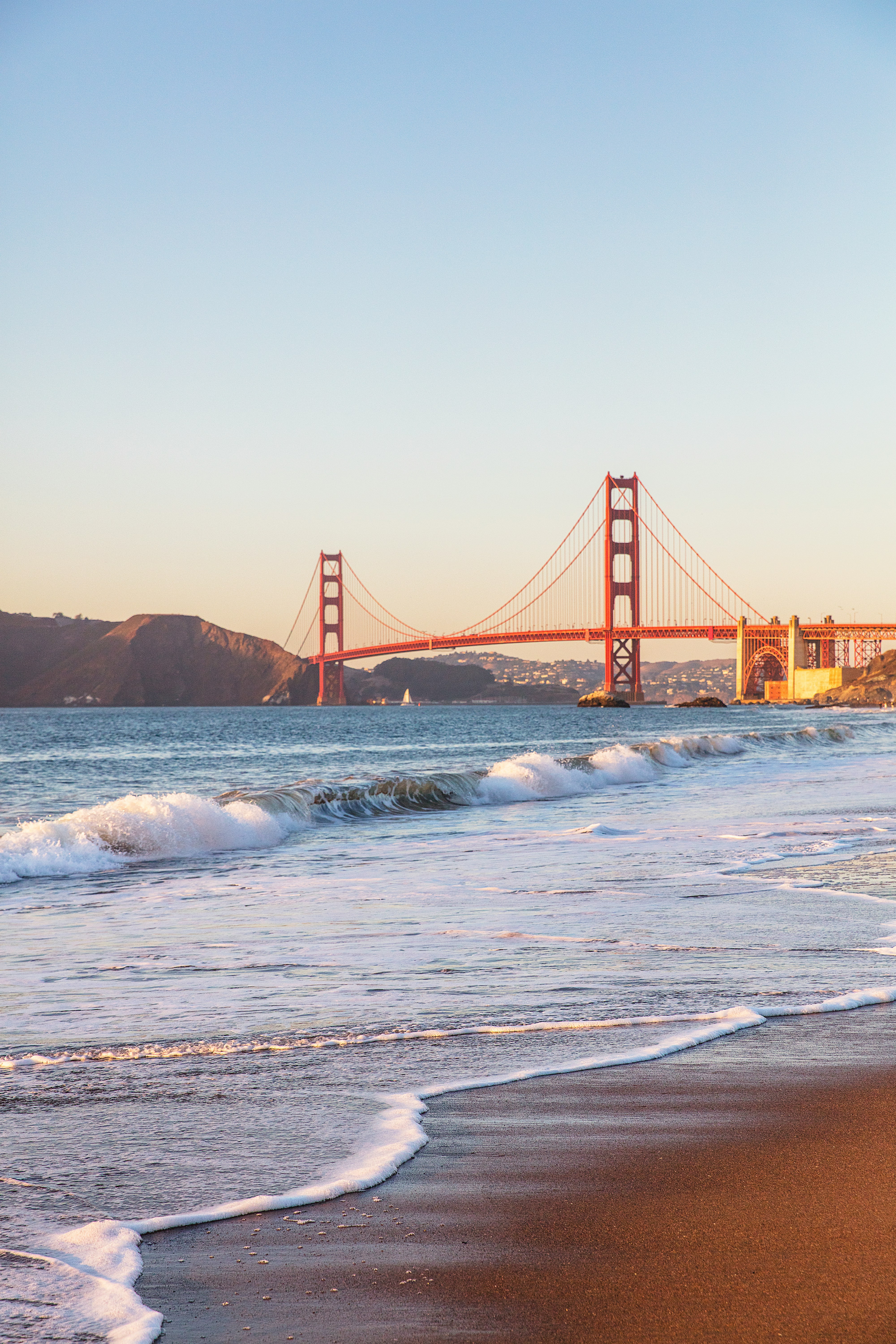 Golden Gate Bridge at sunset with gentle waves on the shore in San Francisco