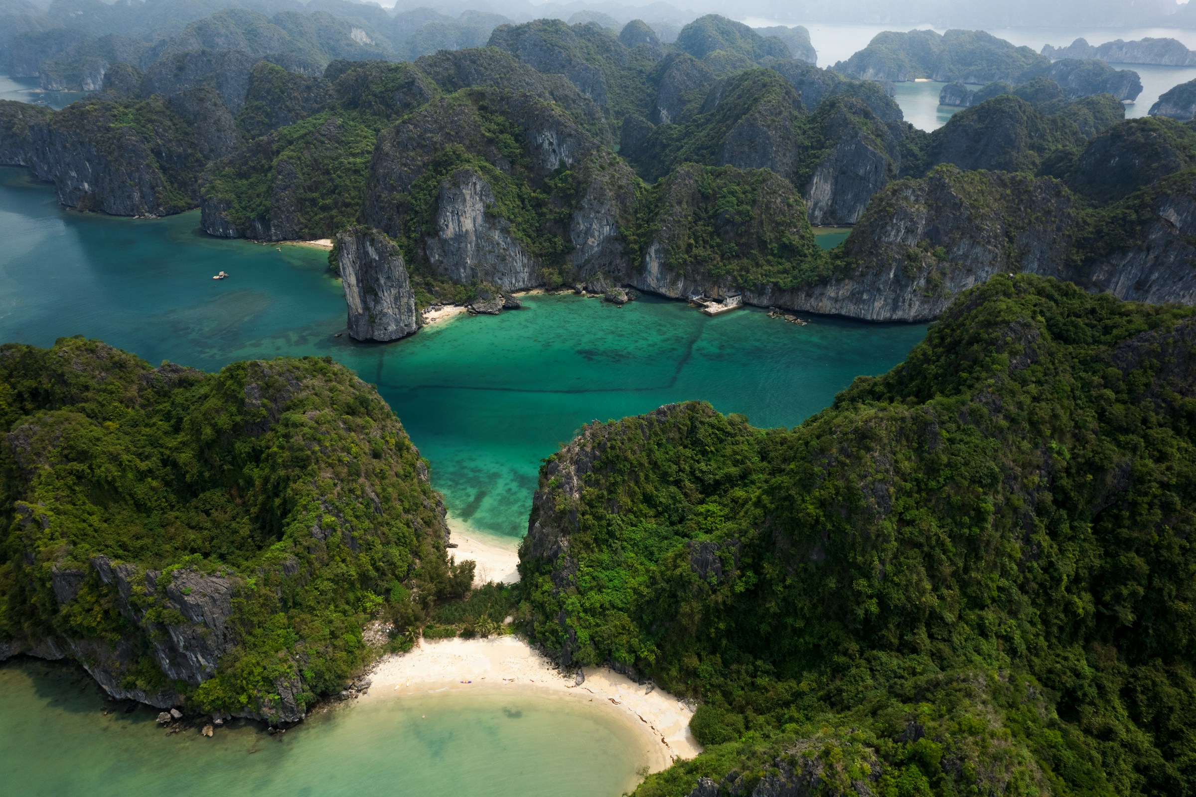 Fågelvy över en vacker bukt med blått hav och grönskande djungel runtomkring i Vietnam