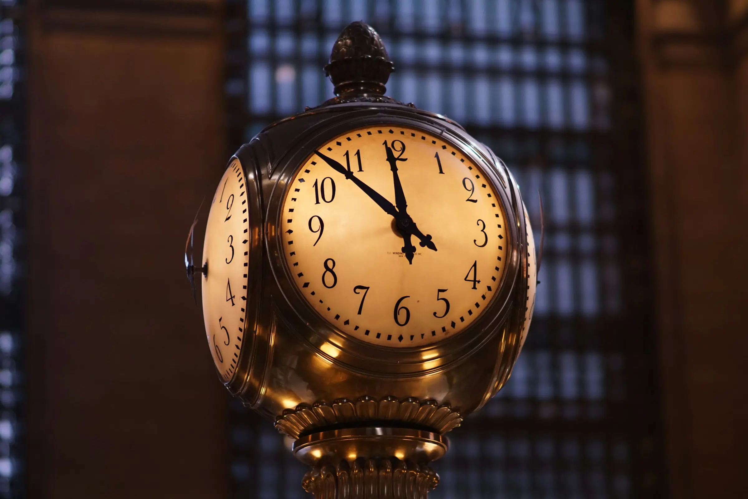Ornate clock inside Grand Central Terminal showing the time as 10:10, with a dimly lit, architectural background